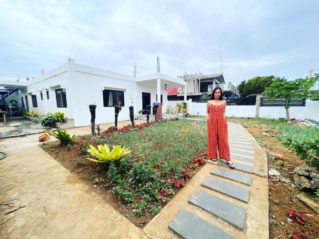Una donna con un vestito rosso in piedi accanto a un giardino di Capinahan Guest House 