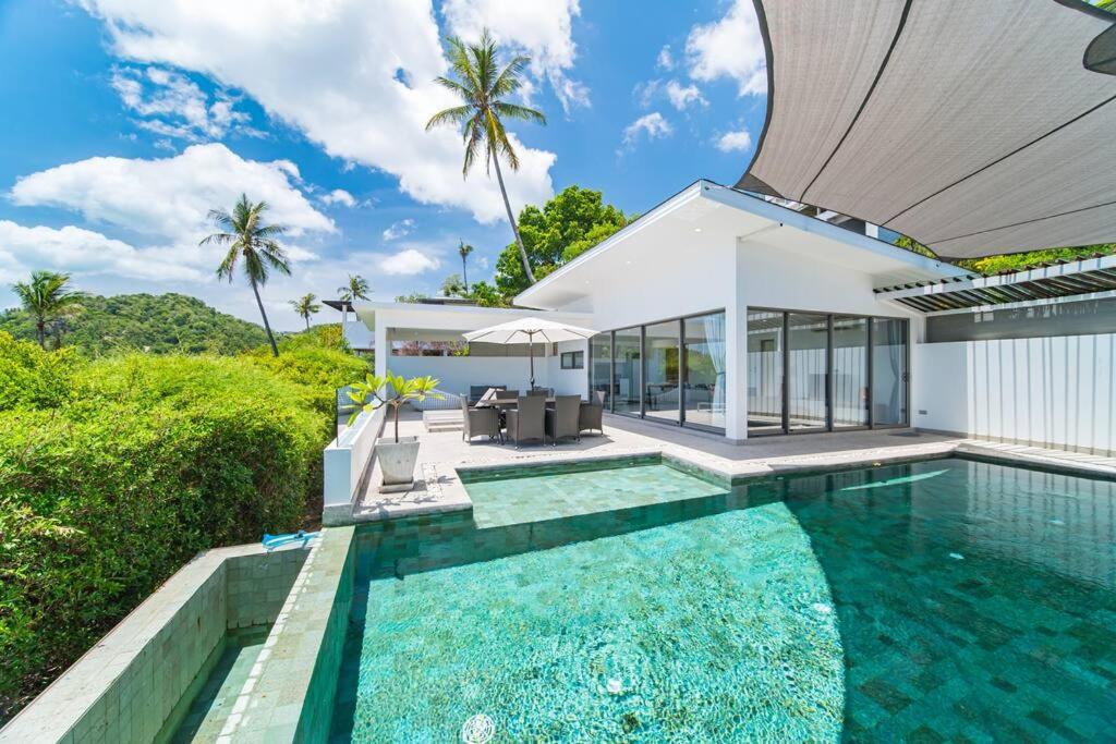 a villa with a swimming pool and a house at Nastha Villa 3 bedrooms in Koh Samui 