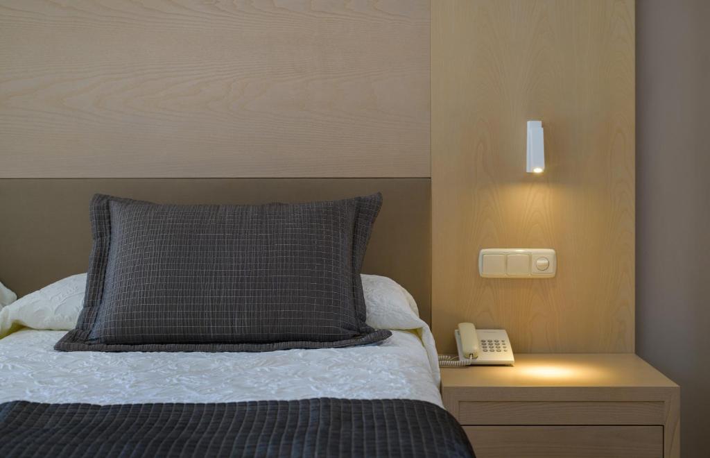 a bed with a pillow and a phone on a night stand at Hipotels Natura Palace Adults Only in Playa Blanca