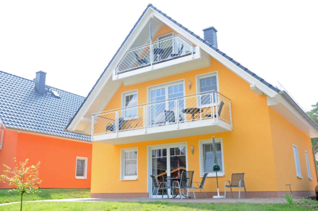 Casa de color amarillo y naranja con balcón en Ferienwohnungen Appartements - Ferienhaus Müritzlust, en Marienfelde