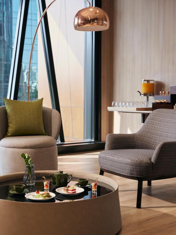 A compact lounge vignette with two armchairs, refreshments, and a tall window.