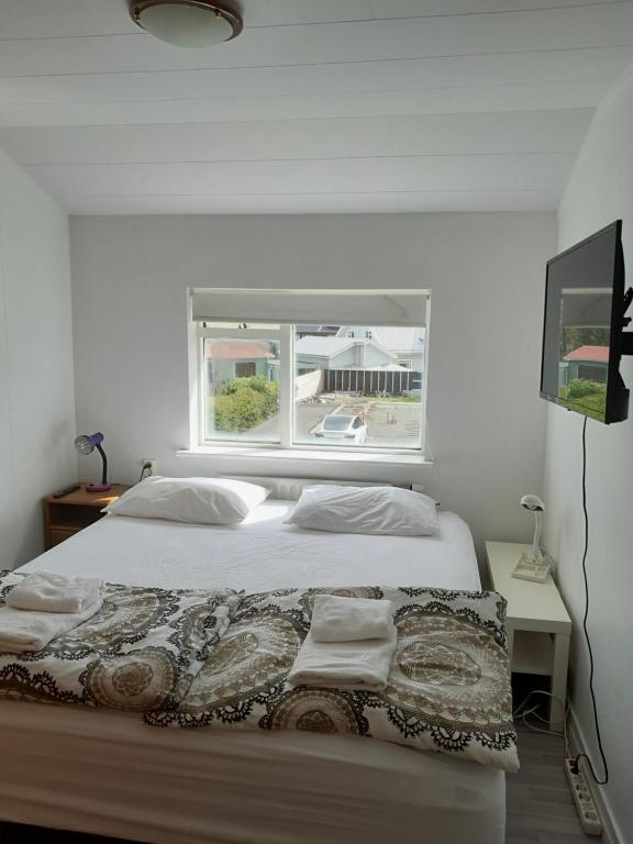 a white bedroom with a bed with a window at Kyrrðarstaður in Selfoss