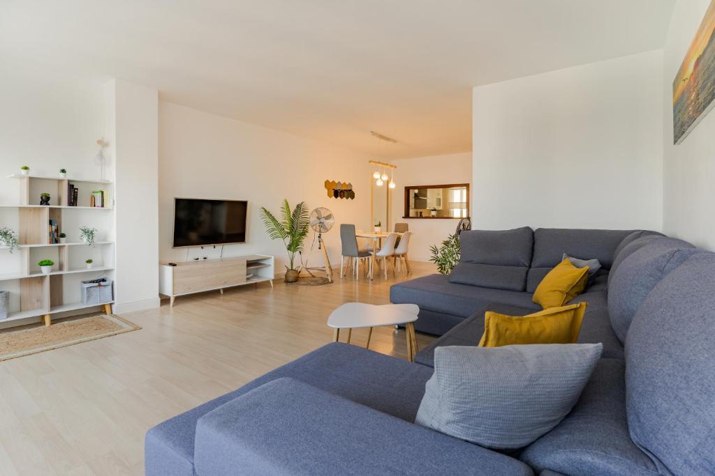 sala de estar con sofá azul y almohadas amarillas en Apartamento frente al mar TORRES DE PLAYAMAR en Torremolinos
