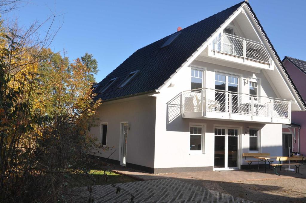 a white house with a black roof at "Ferienwohnungen Appartements - Ferienhaus Müritzglück" in Marienfelde
