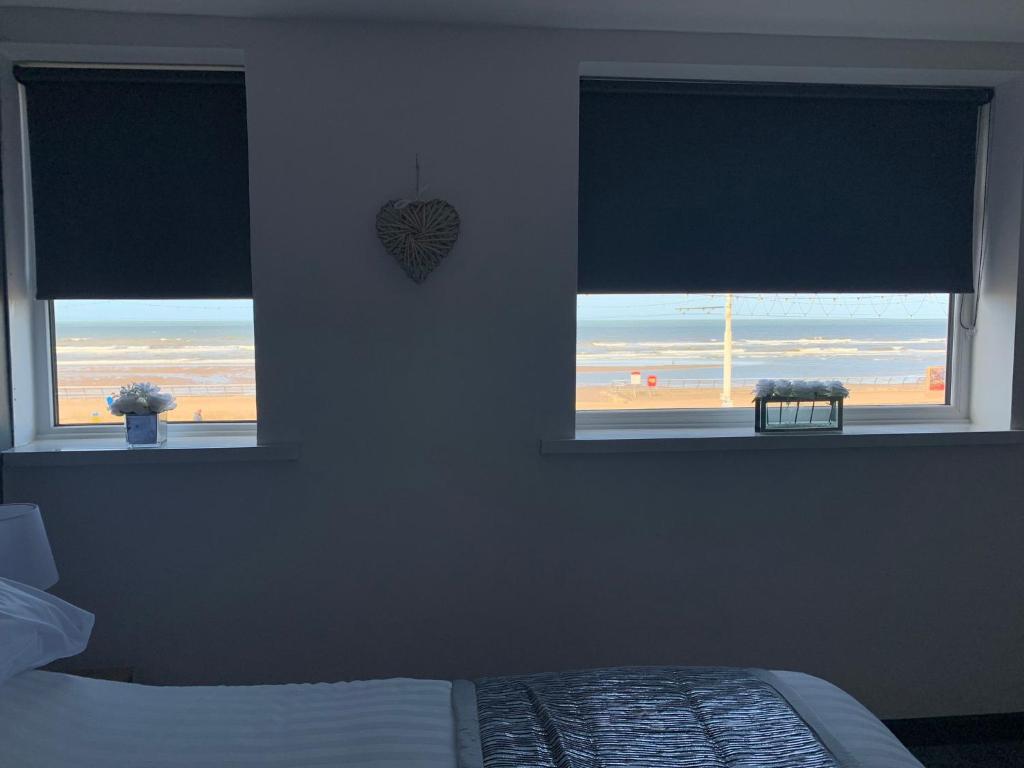a bedroom with two windows with a view of the beach at Woodhouse Hotel Fully refurbished quiet family hotel No stag or hens all will be refused on checkin in Blackpool