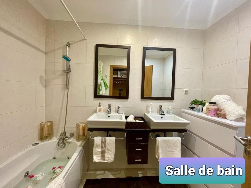 y baño con 2 lavabos, bañera y espejo. en Belle suite / belles vacances, en Olhão
