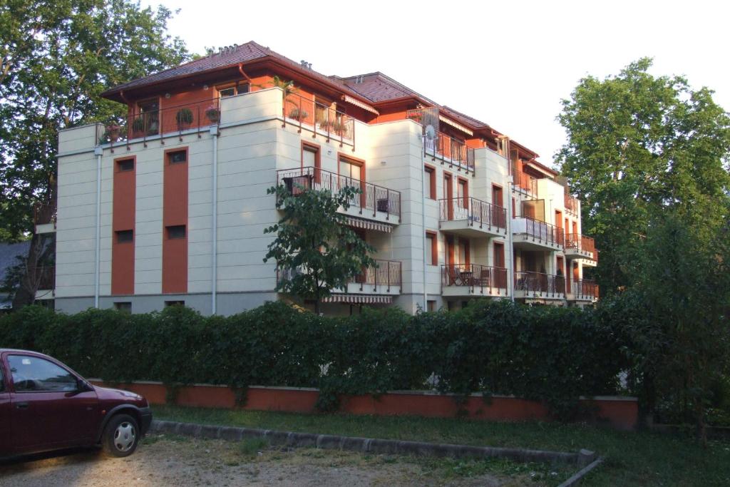 ein weißes Gebäude mit roten Türen und einem Auto vor der Tür in der Unterkunft Villa Palazzo Apartments in Siófok