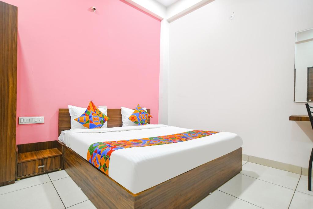 a bed in a room with a pink wall at FabExpress Golden Epoch in Indore