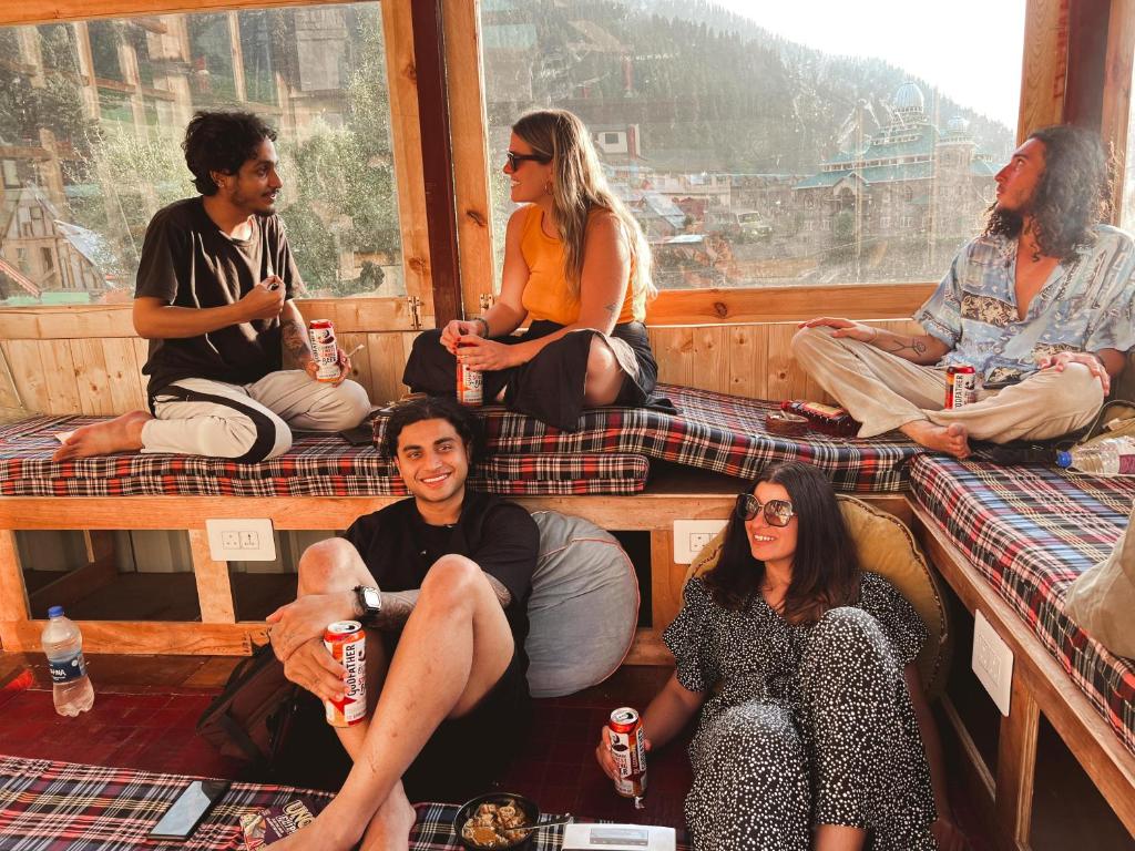 a group of people sitting in a room with drinks at Mitra Hostel Sonamarg in Sonāmarg