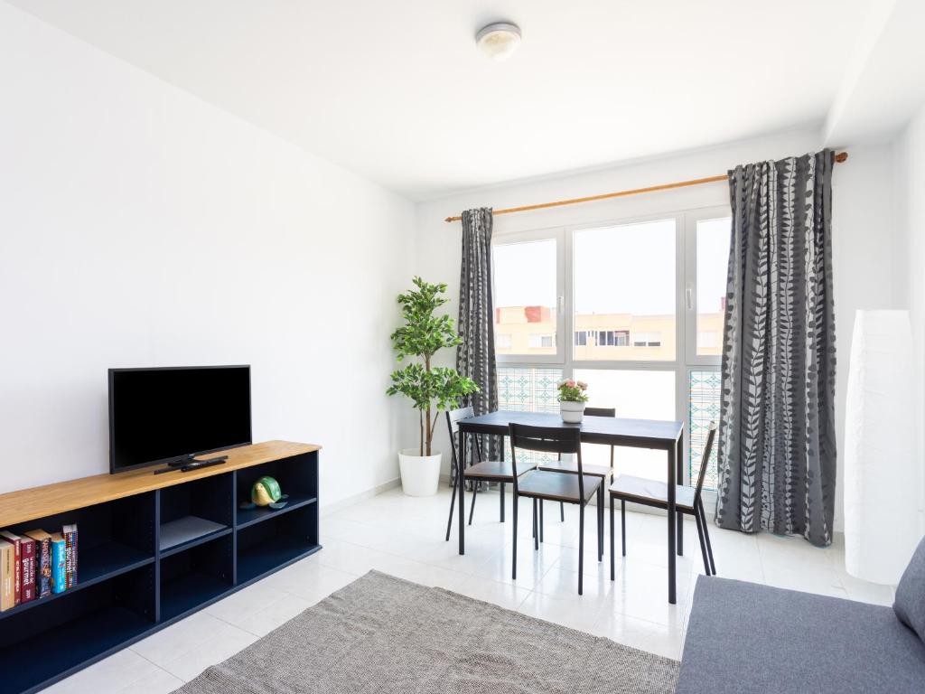a living room with a dining room table and a tv at Live Medano Mirazul in El Médano