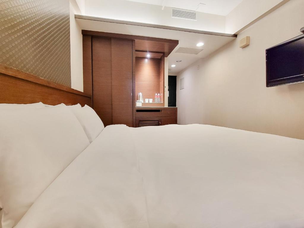 a bedroom with a large white bed and a television at CHECK inn Express Taichung Fengchia in Taichung