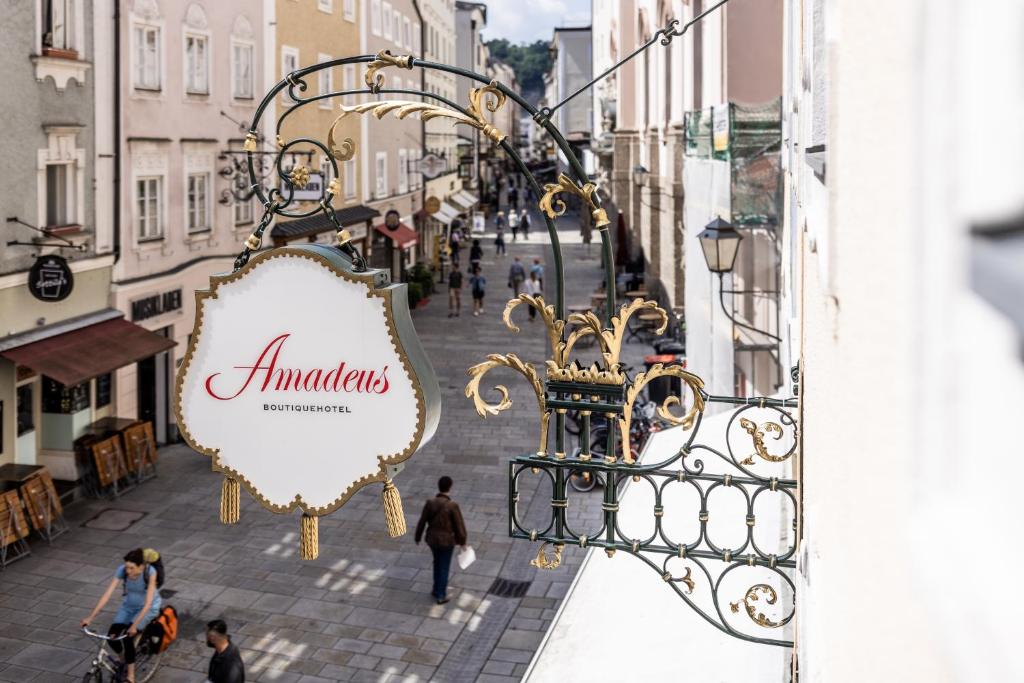 a sign on a balcony of a street with people walking at Boutiquehotel Amadeus in Salzburg