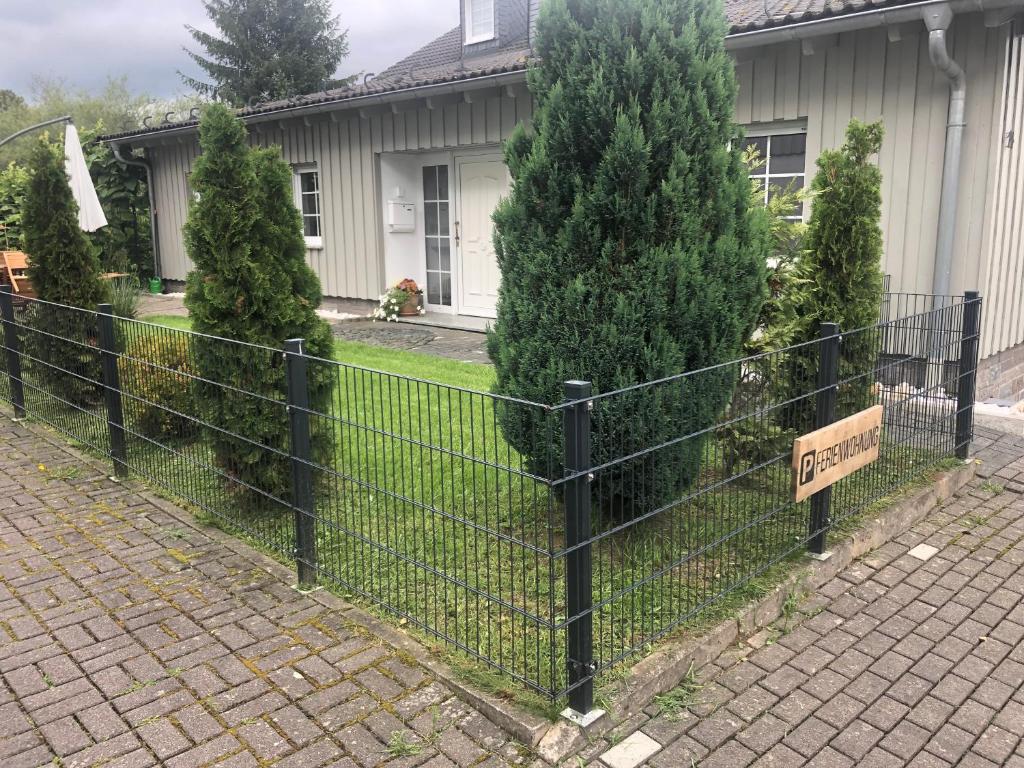 une clôture avec un panneau devant une maison dans l'établissement Ferienwohnung am Rothaarsteig, à Bad Berleburg