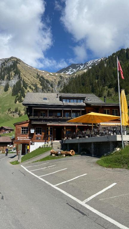 a building with a restaurant with mountains in the background at Restaurant Hotel Schermtanne in Adelboden