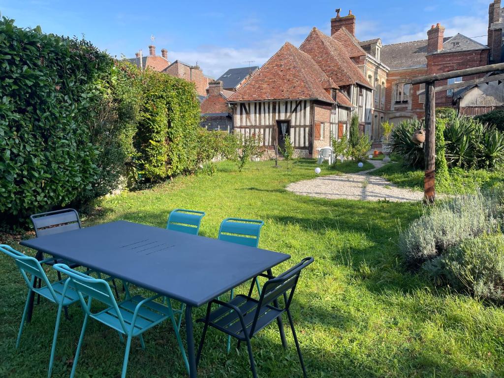 - une table et des chaises dans la cour d'une maison dans l'établissement Le Douet Fleury - Gîte de Jardin, à Livarot