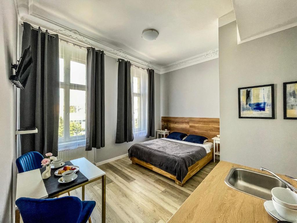 a bedroom with a bed and a table and a sink at Glam House Apartments in Poznań