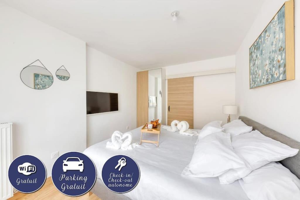 una camera da letto con letto, lenzuola e cuscini bianchi di L'élégant T2 proche de Versailles et de Paris a Guyancourt