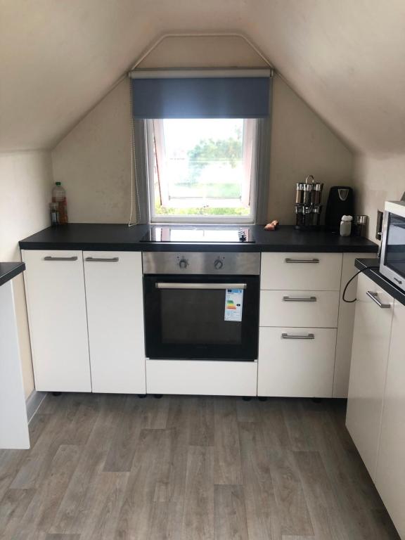 a kitchen with white cabinets and a black stove at Room with shared kitchen in Mill Hill