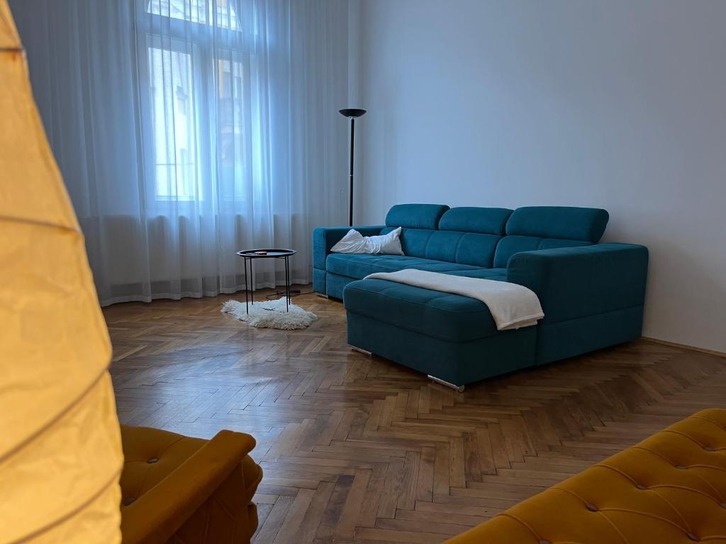 ein Wohnzimmer mit einem blauen Sofa und einem Tisch in der Unterkunft Schäffer Palace in Szeged