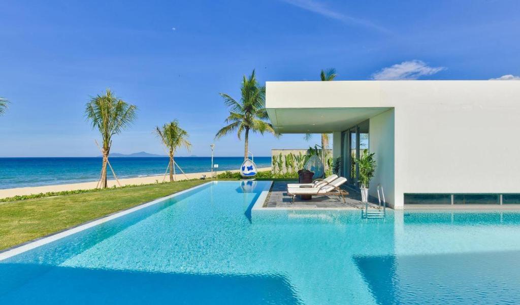 a swimming pool in front of a house with the ocean at Ocean Beach Villas Danang in Da Nang