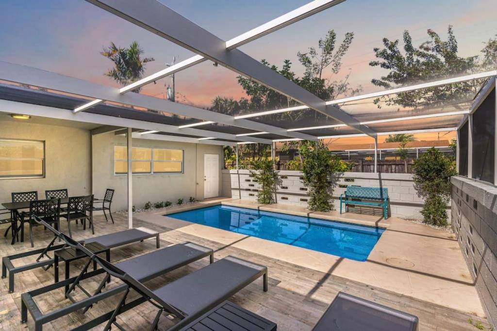 Modern Fort Lauderdale Pool Home في فورت لاودردال: فناء خارجي مع مسبح وطاولات وكراسي