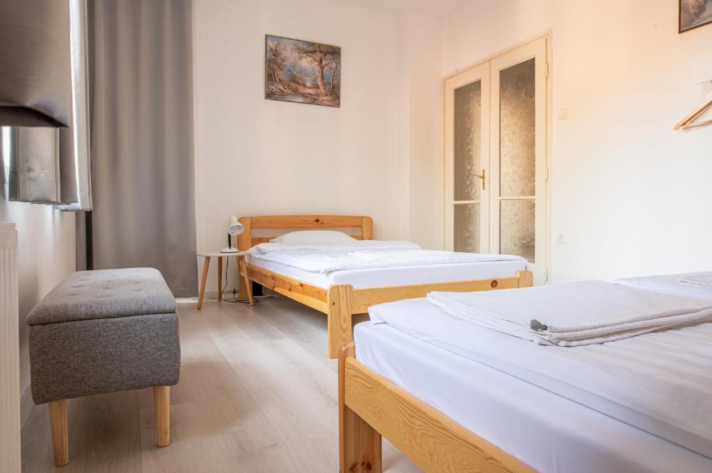 una habitación de hospital con 2 camas y una silla en Barát Vendégház - Cosy Guesthouse - Teljes ház privát udvarral - 4 szoba, 2 fürdő, en Szeged