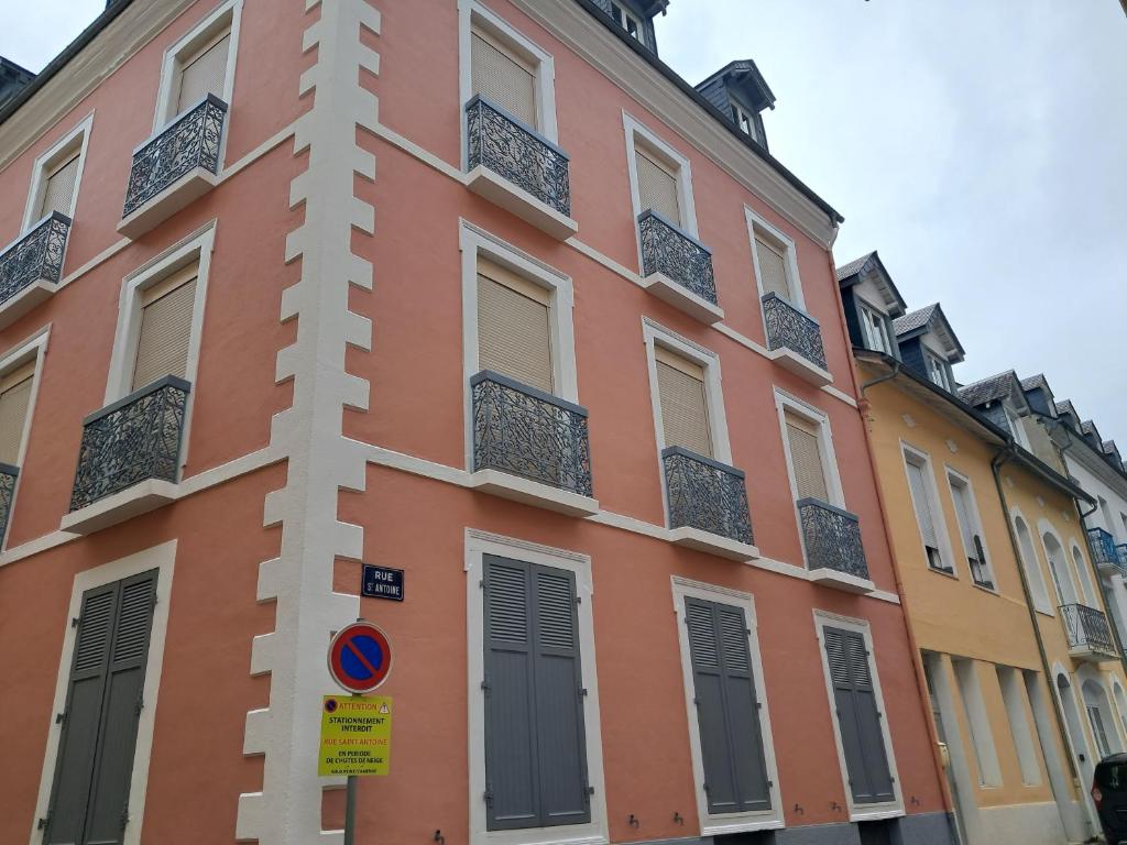 różowy budynek z oknami wychodzącymi na ulicę w obiekcie appartement 3 chambres w mieście Cauterets