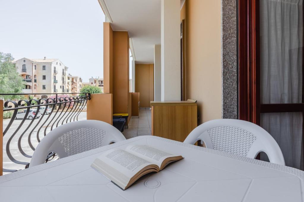 um livro sobre uma mesa com cadeiras e uma varanda em Quartu Sant'Elena - Roomy Apartment with Parking! em Su Forti