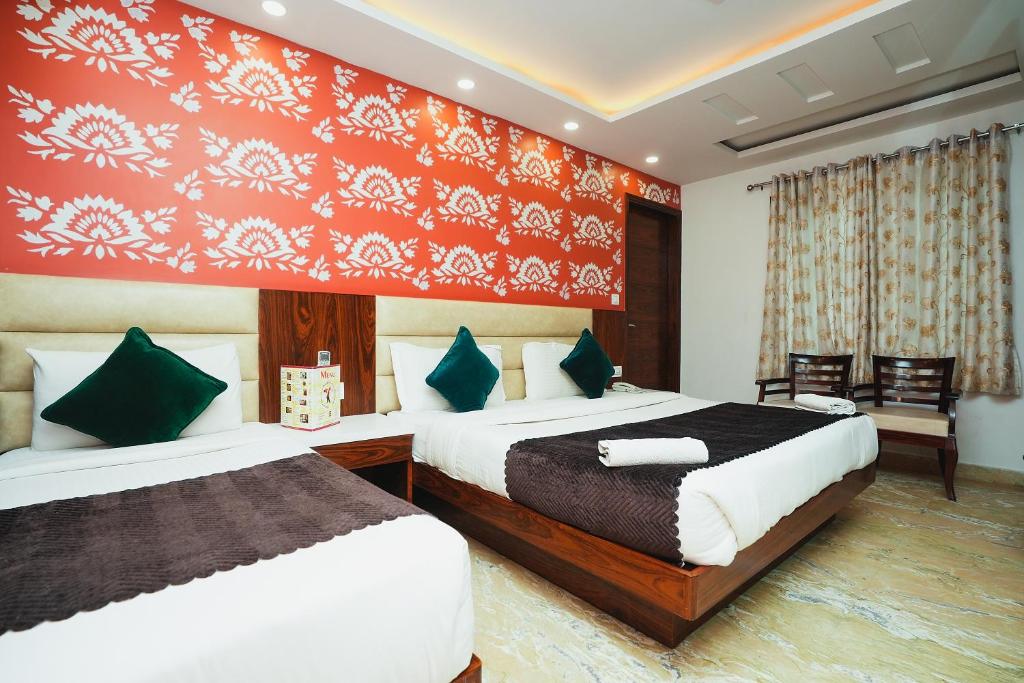 1 dormitorio con 2 camas y pared roja en Hotel Kabir Palace Karol Bagh en Nueva Delhi