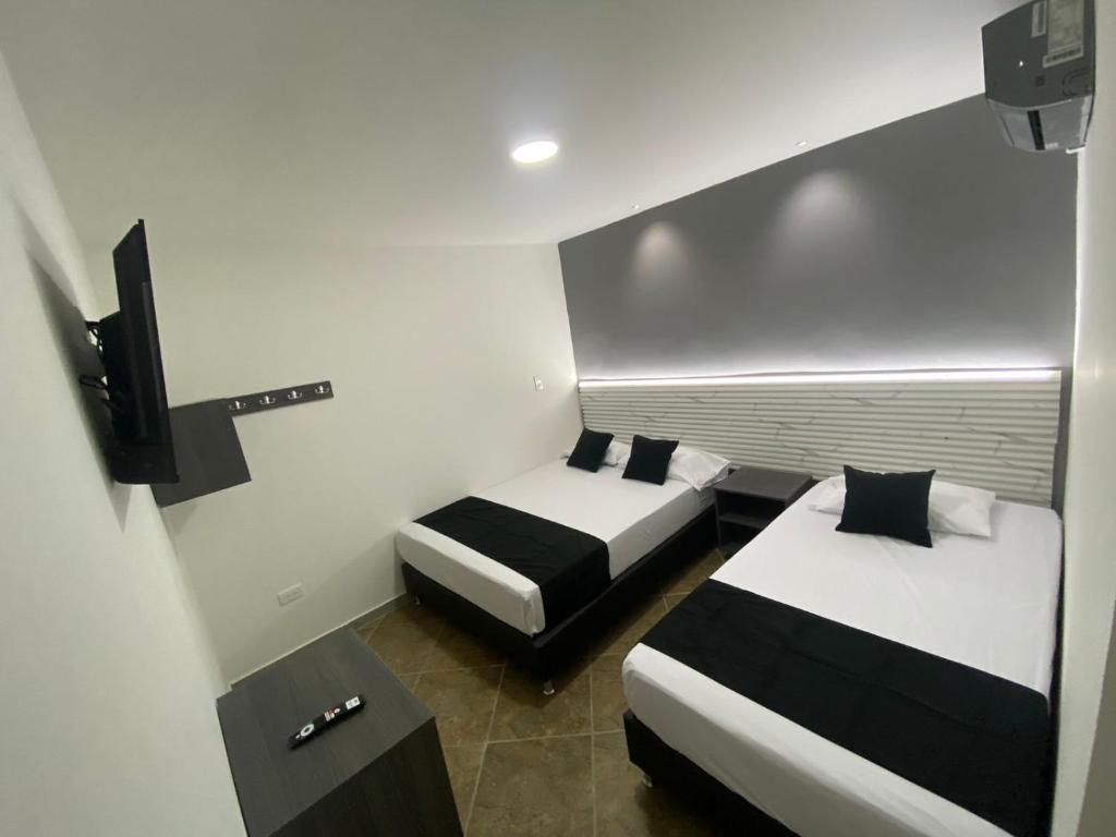 メデジンにあるHOTEL ESTADIO DORADOのベッド2台とテレビが備わるホテルルームです。
