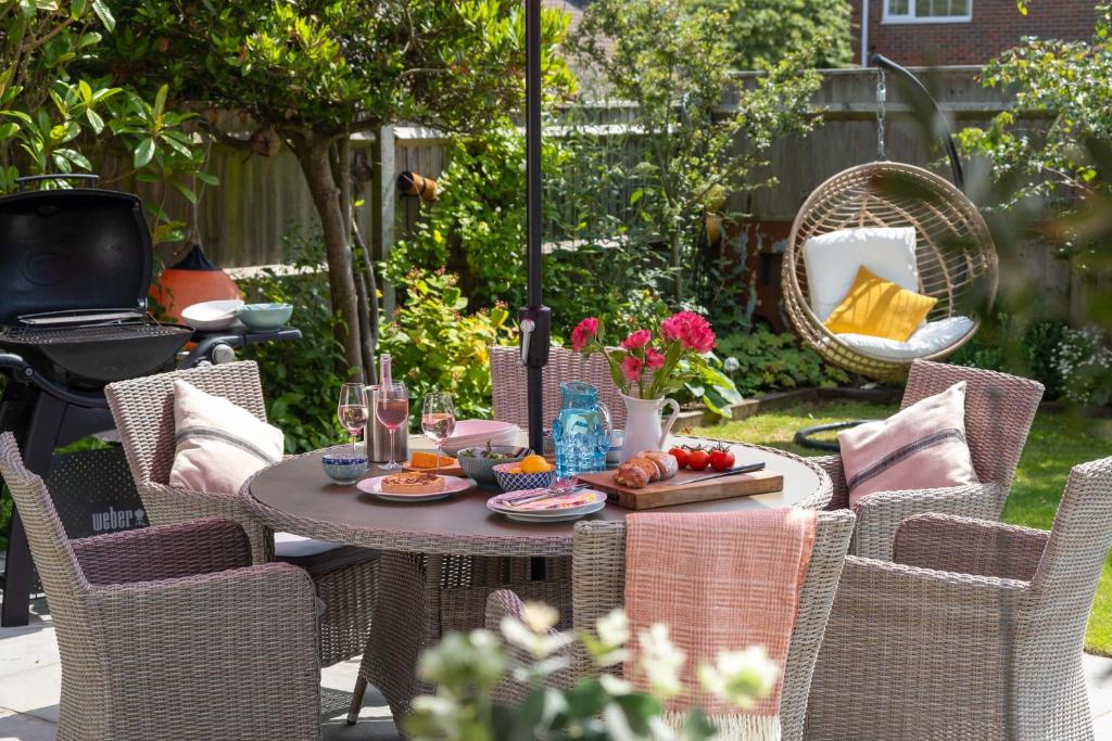 een tafel met eten erop en stoelen in de achtertuin bij Cliff House in Lymington