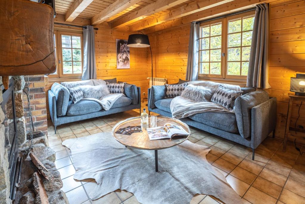 a living room with two couches and a table at Chalet Luxe Les Orchis Alpe d'Huez in LʼHuez