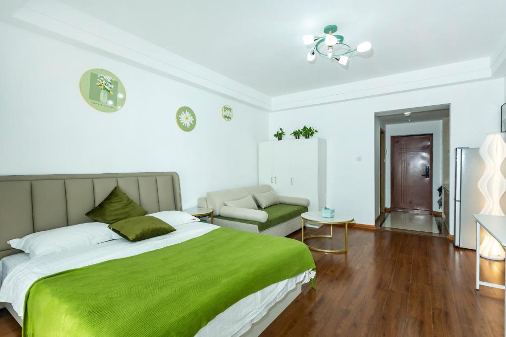 1 dormitorio con 1 cama verde y 1 sofá en Dalian Hong Xi Yuan Apartment Wanda Plaza, en Dalian