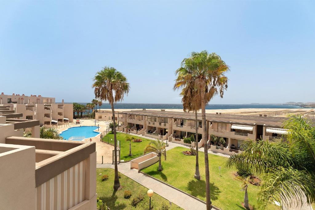 Un edificio de apartamentos con piscina y palmeras. en Duplex Tejita Beach, en Granadilla de Abona
