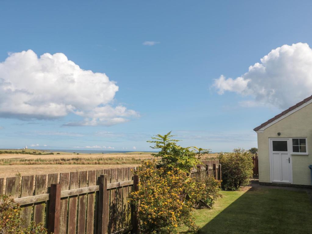ein Zaun und ein Haus mit Blick auf das Meer in der Unterkunft Island View Cottage in Morpeth