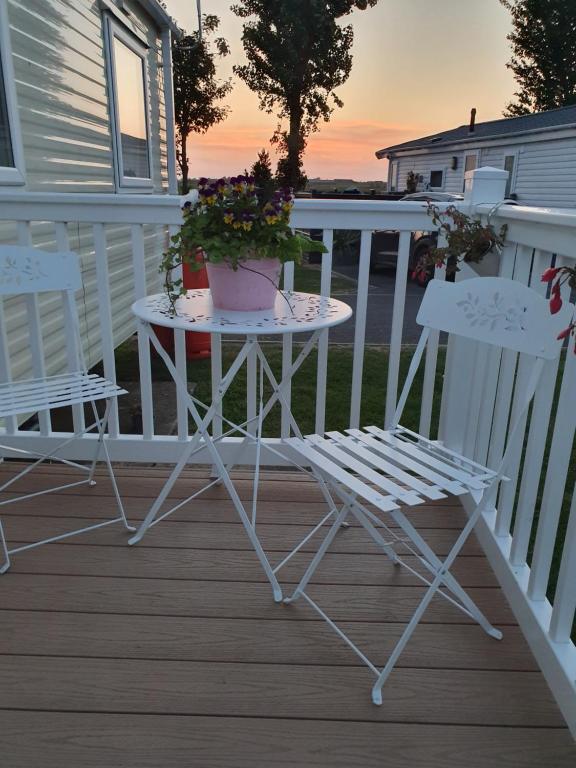 twee stoelen en een tafel op een veranda met een plant bij Kjs holiday home in Saint Osyth