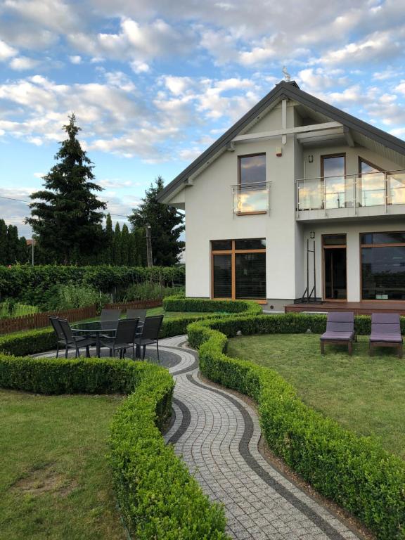 a house with a garden with benches in front of it at Dom nad Zalewem Zegrzyńskim in Nieporęt