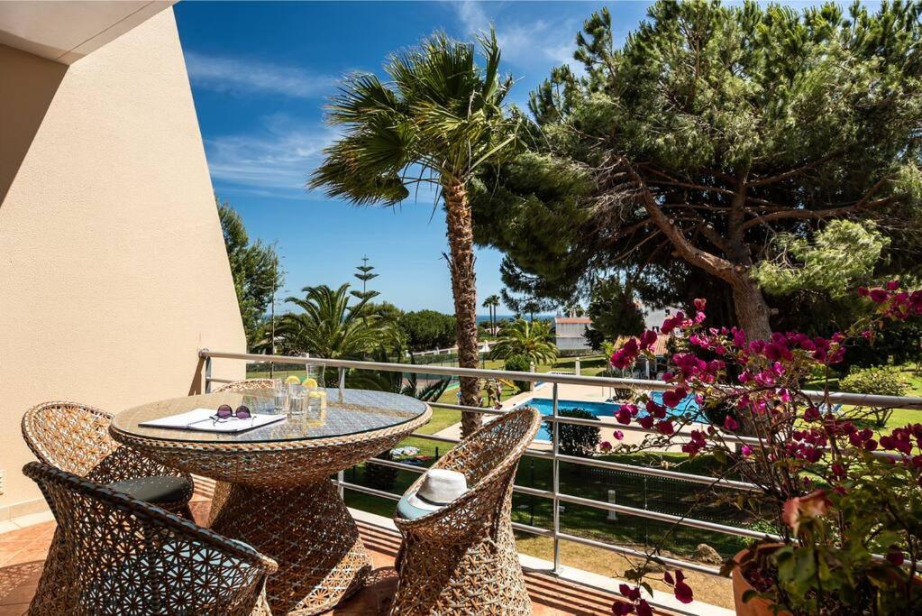 ein Tisch und Stühle auf einem Balkon mit Palmen in der Unterkunft Townhouse Senhora da Rocha - Alporchinhos in Armação de Pêra