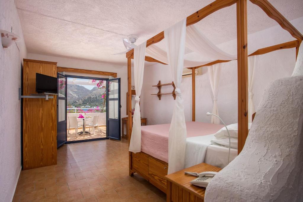 a bedroom with a canopy bed and a desk with a laptop at ILIDI Rock in Livadia