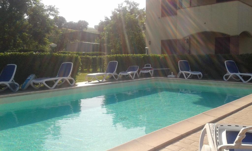 a swimming pool with blue chairs and a group at L'Oasi Residence in Istia dʼOmbrone