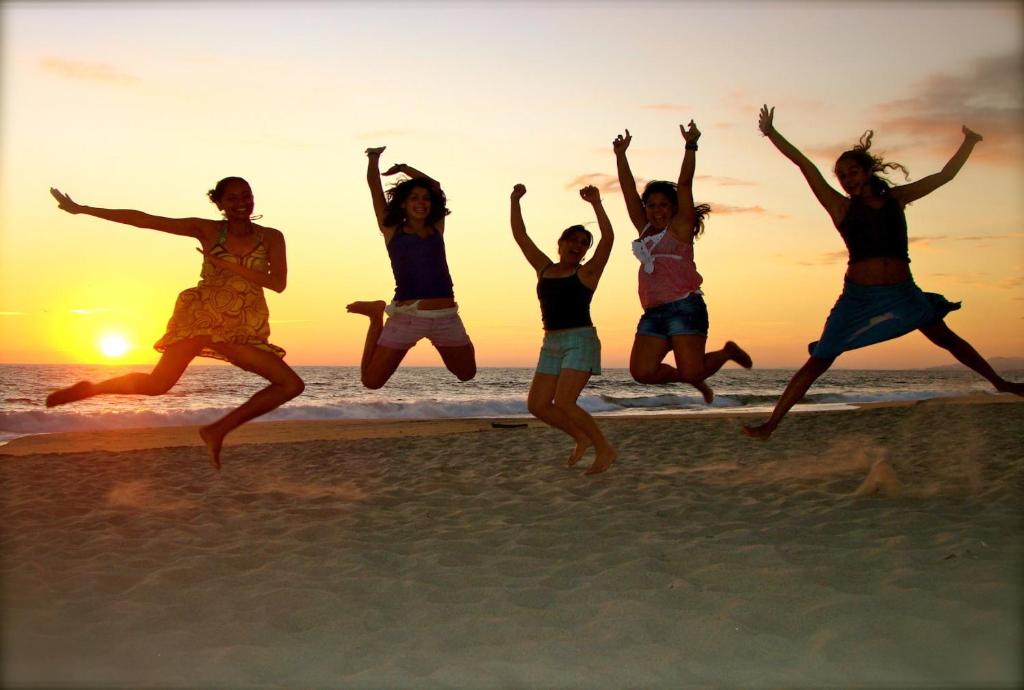 a group of girls jumping on the beach at sunset at Casa Losodeli & Coworking- Adults Only in Puerto Escondido