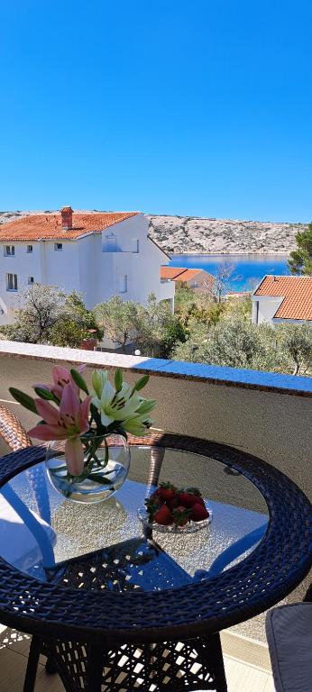 a table with a vase of flowers on a balcony at Apartments Sole in Rab
