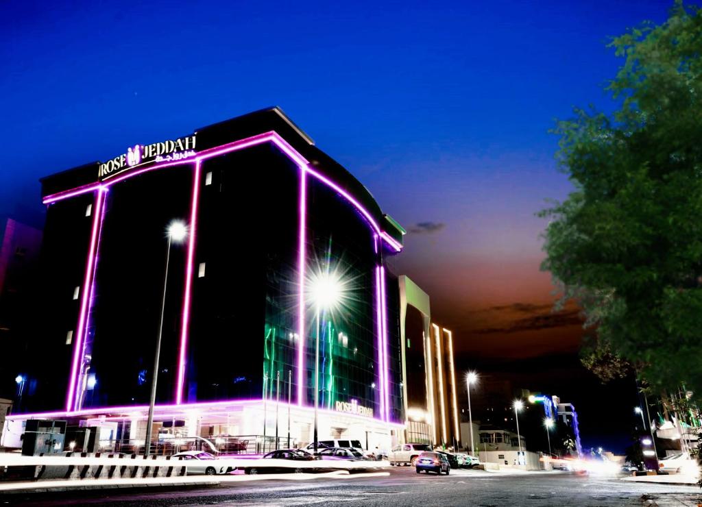 um grande edifício com luzes roxas à noite em Rose Jeddah Hotel em Jeddah