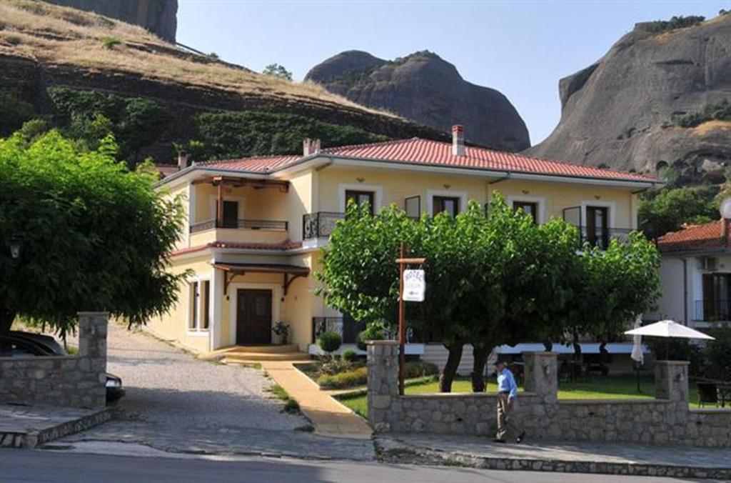 a large yellow house in front of a mountain at Hotel Gogos in Kalabaka
