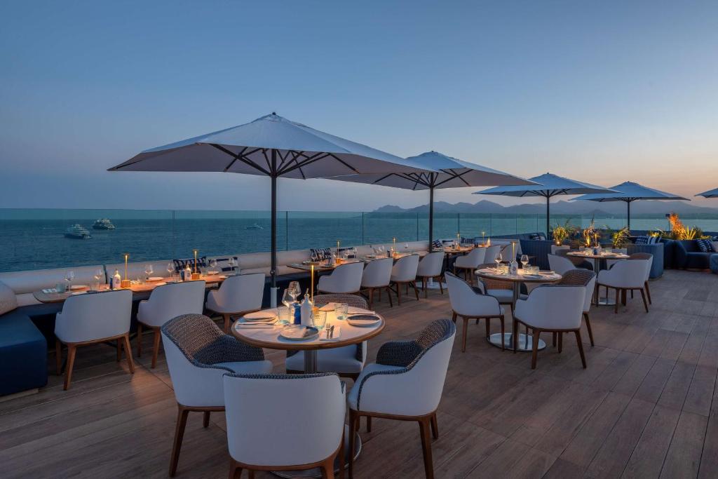 a restaurant with tables and chairs and a view of the ocean at Canopy by Hilton Cannes in Cannes