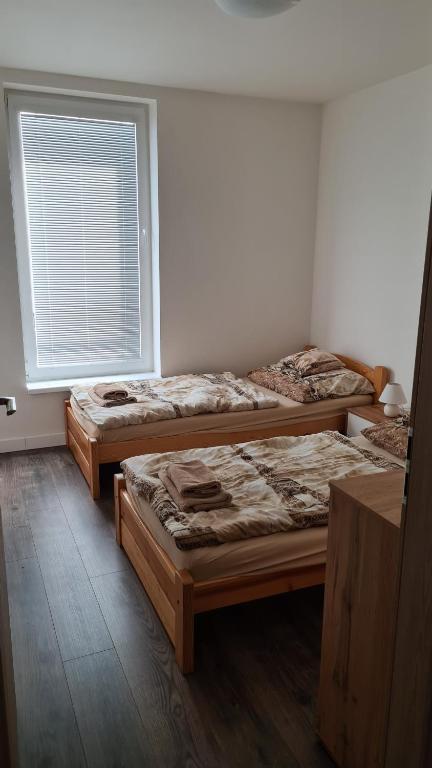 3 Betten in einem Zimmer mit Fenster in der Unterkunft Flower apartman in Dunajská Streda