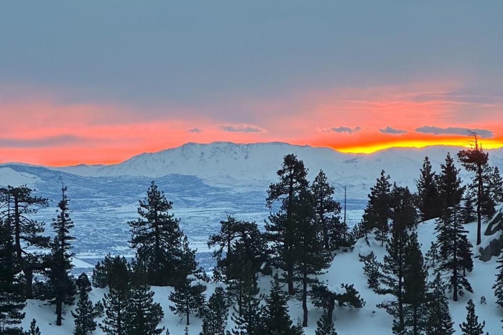 einen Sonnenuntergang über einem schneebedeckten Berg mit Bäumen in der Unterkunft Sunrise Serenity at Tahoe Village in Stateline