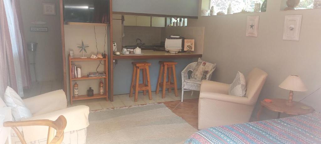 Zimmer mit einem Bett und Stühlen sowie einer Küche in der Unterkunft 1 bed garden flat in Umzumbe