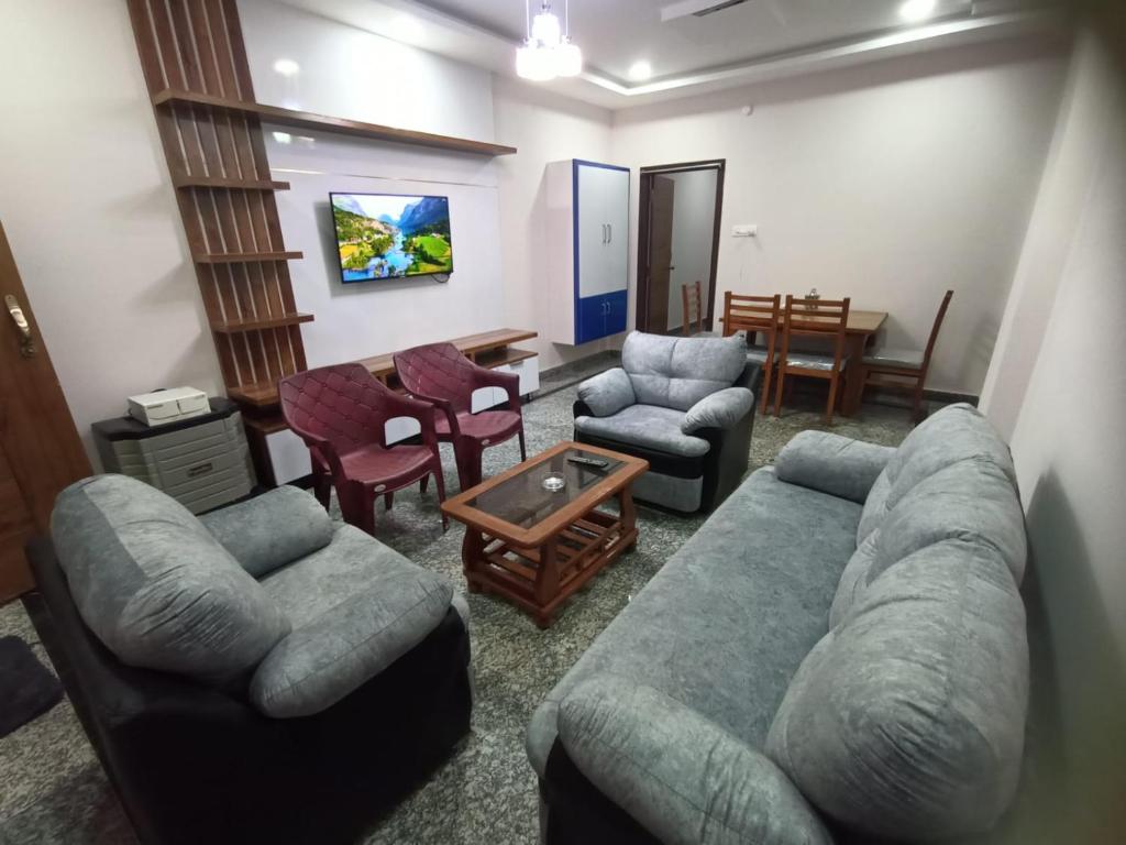 een woonkamer met een bank, stoelen en een tafel bij New Premium Fully Furnished 2 BHK Flats Near Station in Tirupati