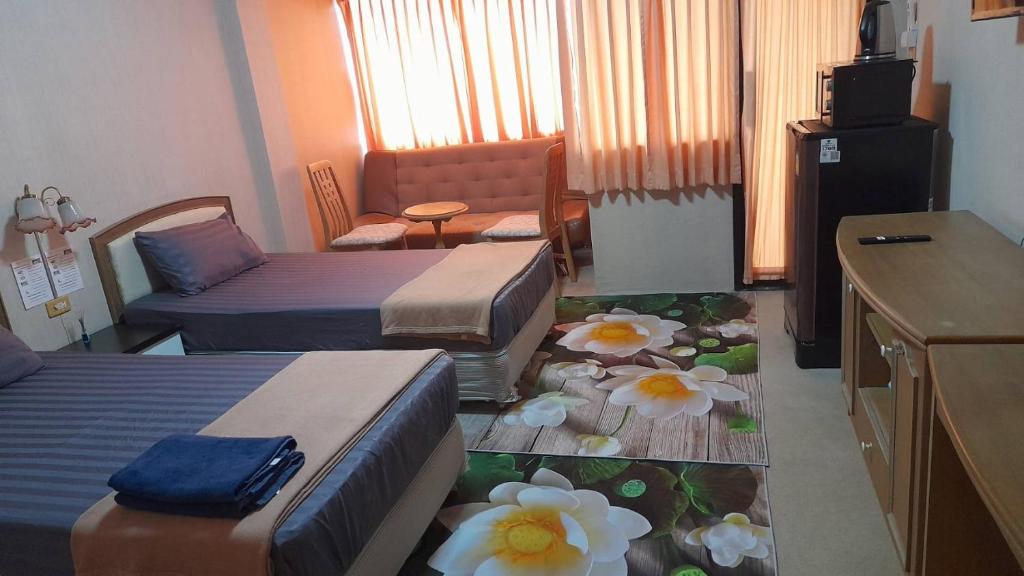 a hotel room with three beds and flowers on the floor at Victory view rayong beach in Ban Chamrung